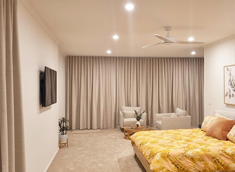 Large, cosy master suite with yellow bedlinen and neutral blockout curtains.