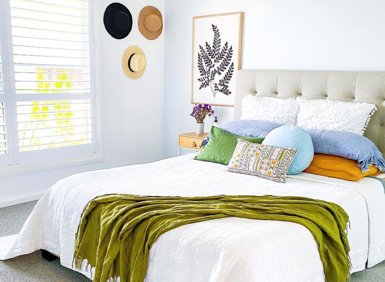 A bright, fresh main bedroom with vibrant styling and plantation shutters on the windows.