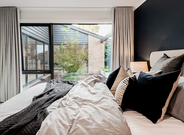 Moody bedroom with grey blockout curtains open to the courtyard outside.