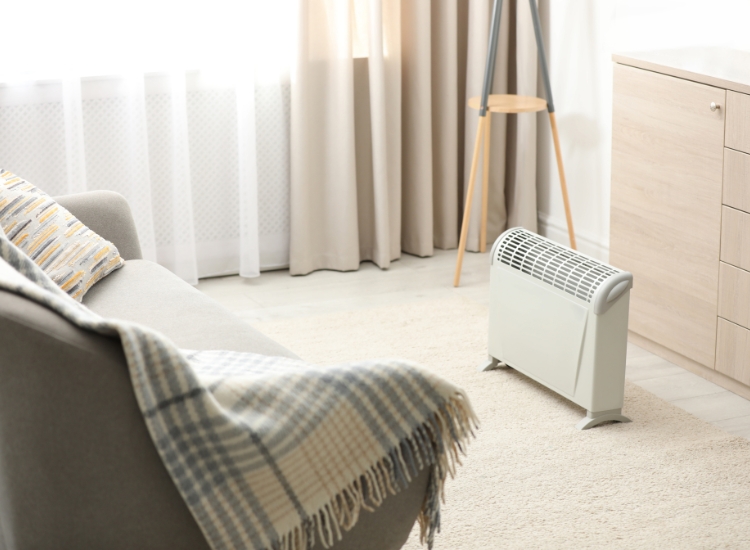 A scandi-style living room featuring an electric heater and couch with double curtains on the window in the background.