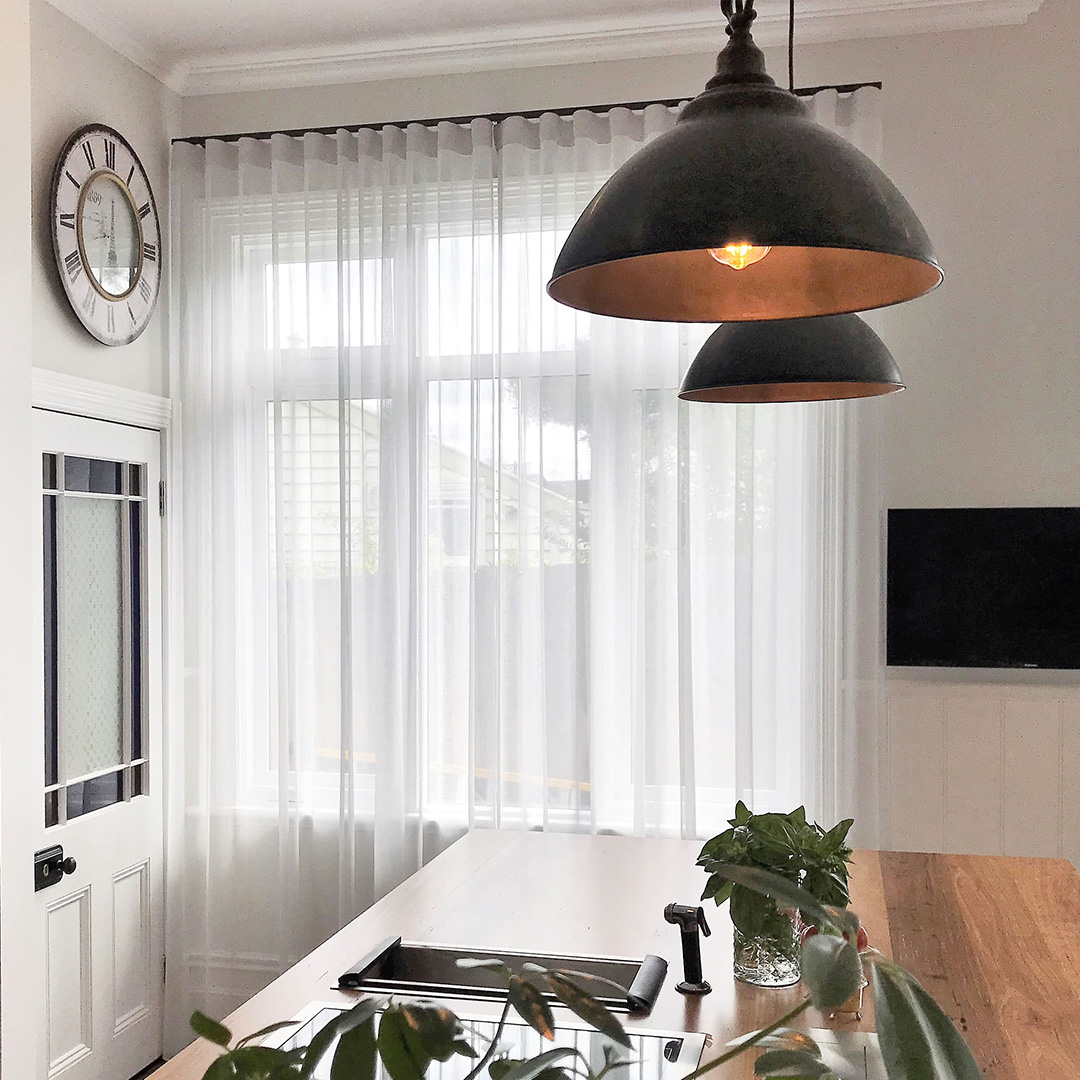 Light grey sheer curtains with black tracks, on two windows of a heritage dining room. 