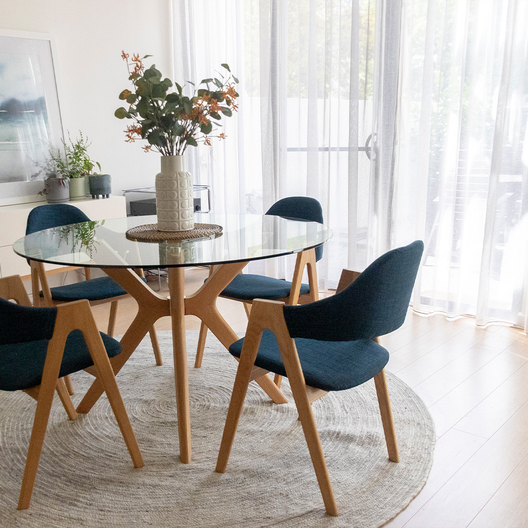 Contemporary styled dining area with round table and beautiful sheer curtains covering the sliding doors 