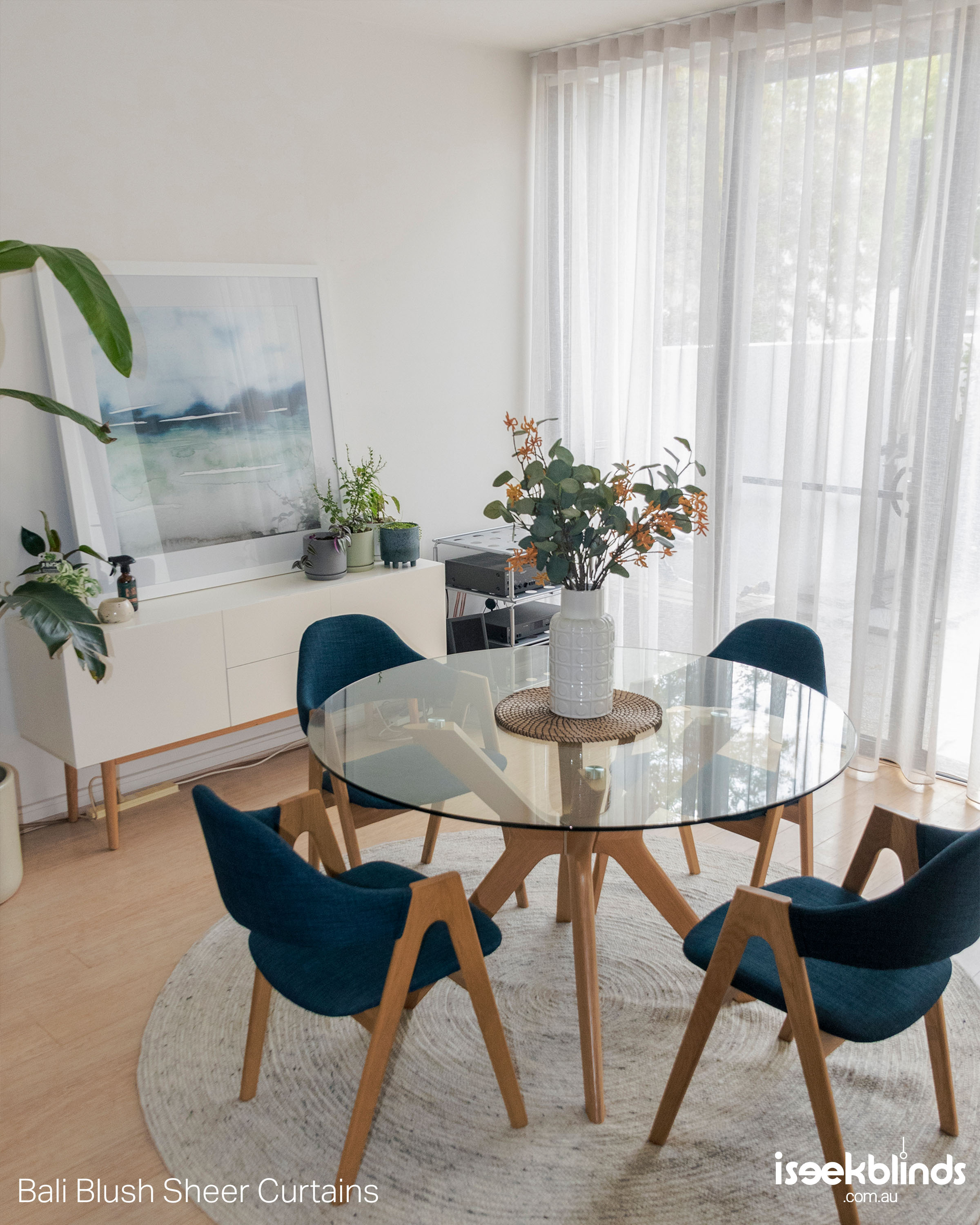 Beautiful sheer curtains in a cosy dining room with a round table and blue chairs.